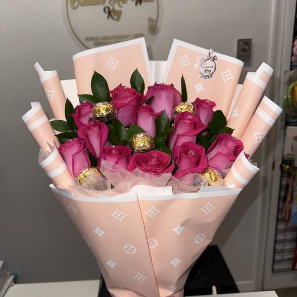 Pink rose bouquet wrapped in peach paper with a satin bow and chocolates