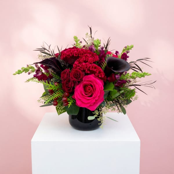Pink and red floral arrangement in a black vase