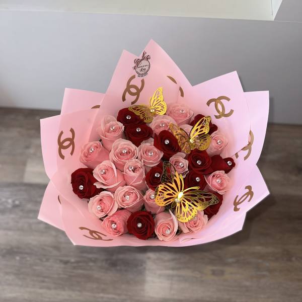 Pink and red rose bouquet wrapped in pink paper with butterfly accents