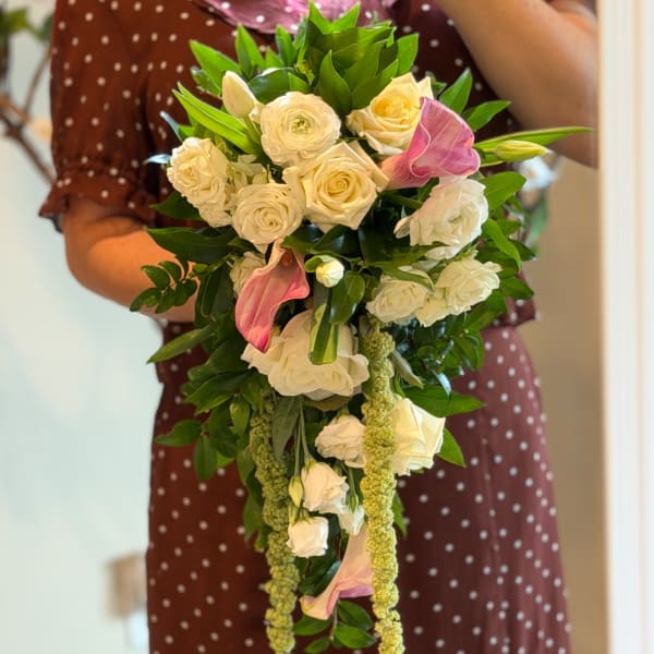 Bouquet of white roses and pink calla lilies with trailing greenery