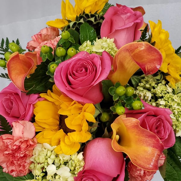 Mixed bouquet with pink roses, yellow sunflowers, orange calla lilies, and carnations