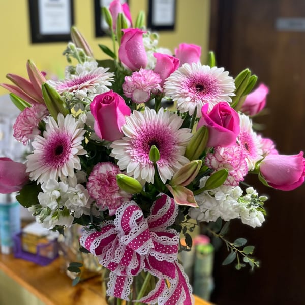 Pink and white mixed bouquet with roses, daisies, and lilies tied with a ribbon