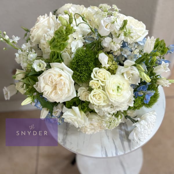White and blue mixed bouquet in a round vase on a small table
