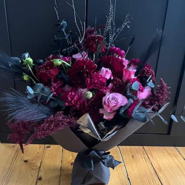 Bouquet of dark red and pink flowers wrapped in black paper