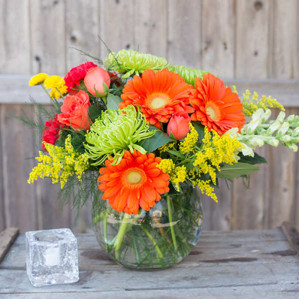 Bright mixed bouquet in a clear glass vase with orange gerberas and pink roses
