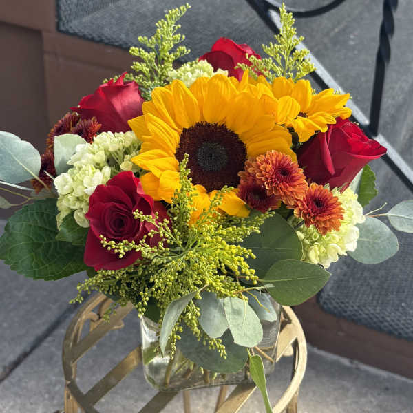 Bouquet with a sunflower, red roses, and orange mums in a glass vase