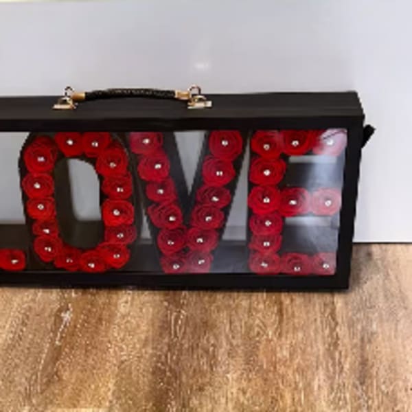 Black display case with red roses arranged to spell LOVE