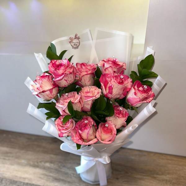 Bouquet of pink roses wrapped in white paper with a ribbon