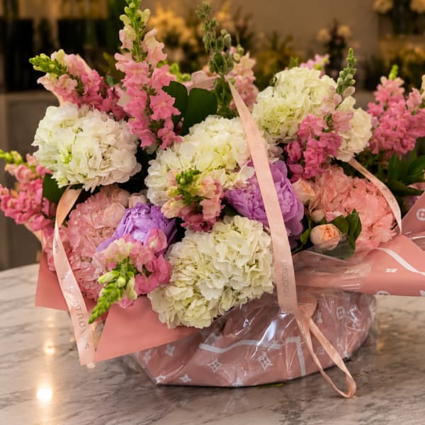 Bouquet of pink and white hydrangeas with snapdragons in pink wrapping