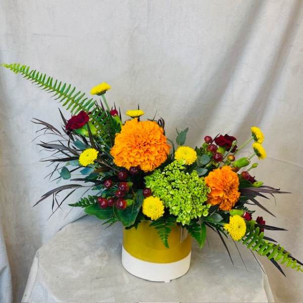 Orange and yellow floral arrangement in a yellow-and-white vase