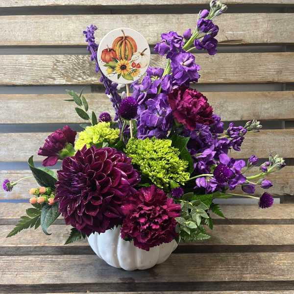 Purple and magenta floral arrangement in a white pumpkin vase