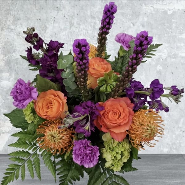 Bouquet of orange roses and purple flowers with green foliage