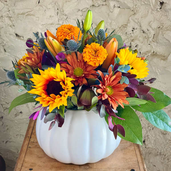 Mixed bouquet in a white pumpkin vase with sunflowers, mums, and lilies
