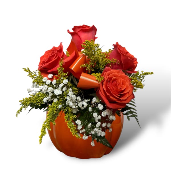 Red roses arranged in an orange pumpkin-shaped container with ribbon