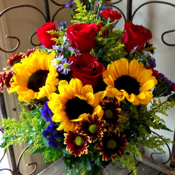 Bouquet of red roses and sunflowers in a glass vase