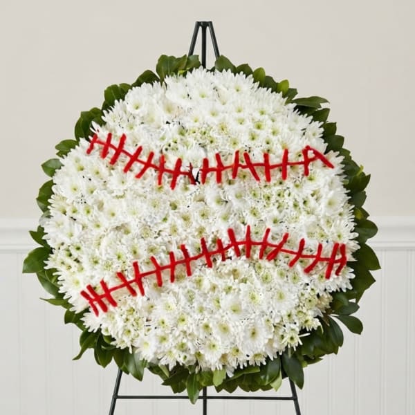 Round white chrysanthemum wreath with red ribbon accents on a stand