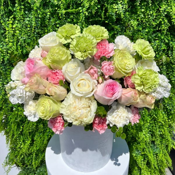 Round bouquet of pink, white, and green flowers in a white vase