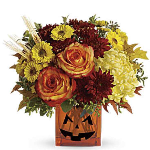 Fall flower arrangement in a jack-o'-lantern vase with roses and mums