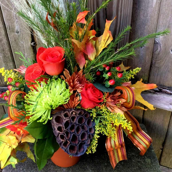 Autumn floral arrangement with red roses and mixed foliage in a vase