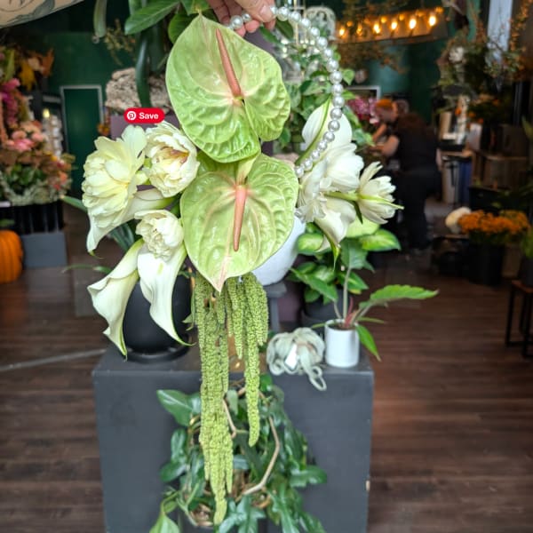 Wedding floral arrangement with white blooms, green anthuriums, and pearl accents