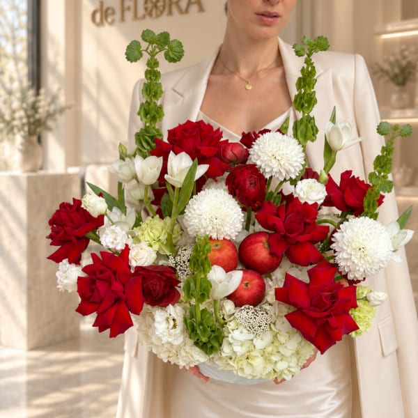 Woman holding a bouquet of red and white flowers with apples