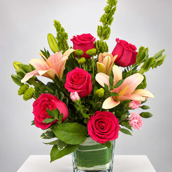 Pink roses and lilies arranged in a clear glass vase