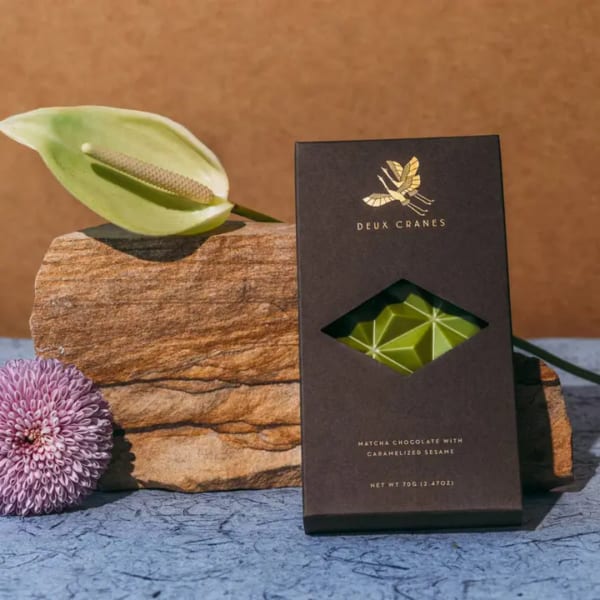 Chocolate bar box beside a white anthurium and purple chrysanthemum