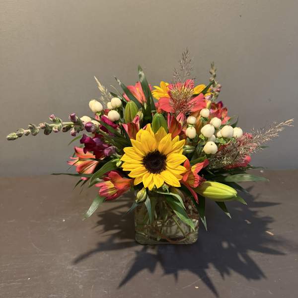 Mixed bouquet with a sunflower in a square glass vase