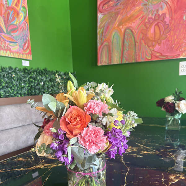 Mixed bouquet in a clear glass vase with pink, orange, purple, and white flowers