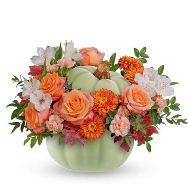 Orange and white floral arrangement in a pale green pumpkin vase
