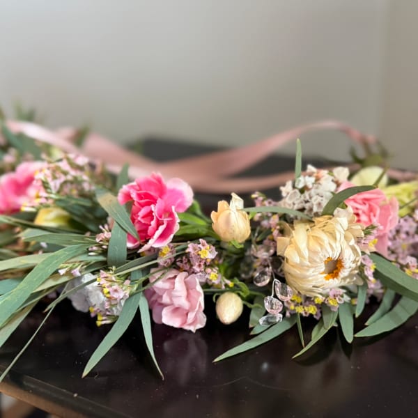 Pink and cream floral arrangement with ribbon on a dark surface