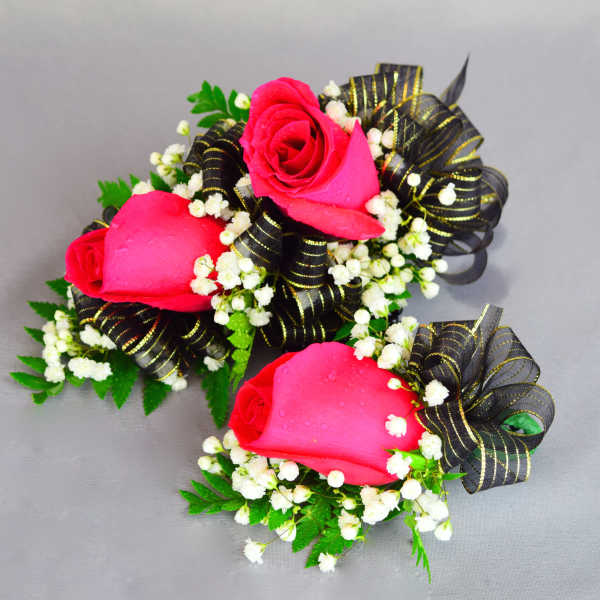 Two pink rose corsages with black ribbon and white filler flowers