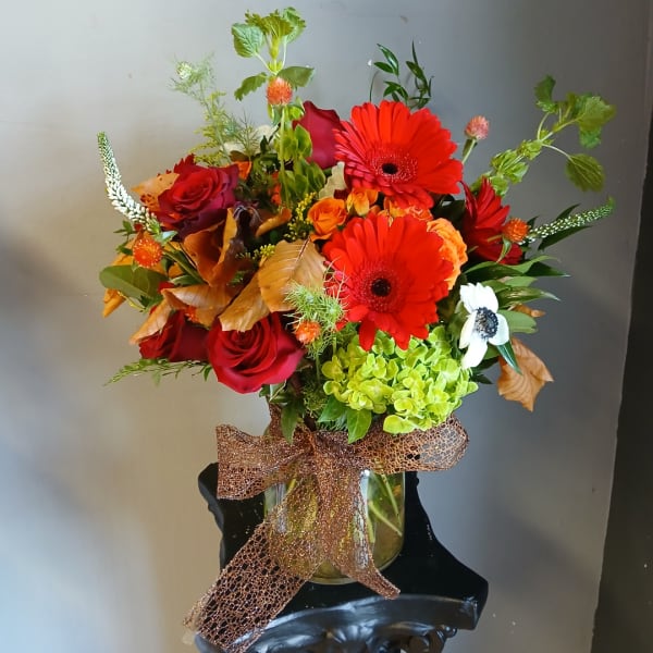 Mixed bouquet of red roses and bright gerbera daisies in a glass vase