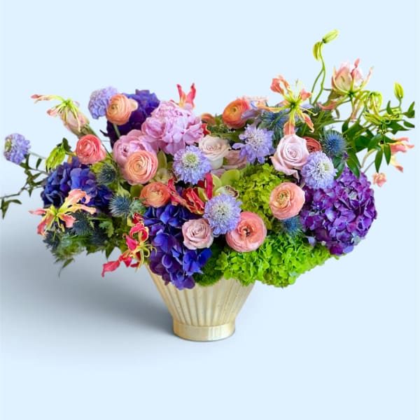 Colorful mixed bouquet in a gold vase with pink, purple, and green blooms