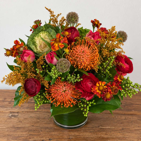 Bright mixed bouquet in a glass vase with red, orange, and pink blooms