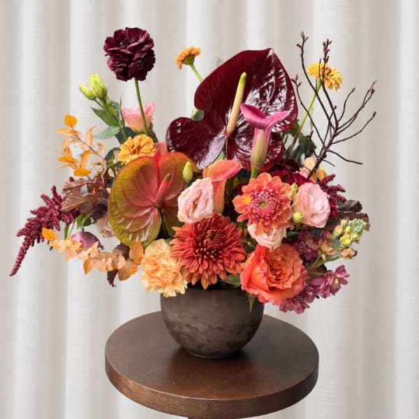 Colorful floral arrangement in a dark vase with anthuriums and mixed blooms