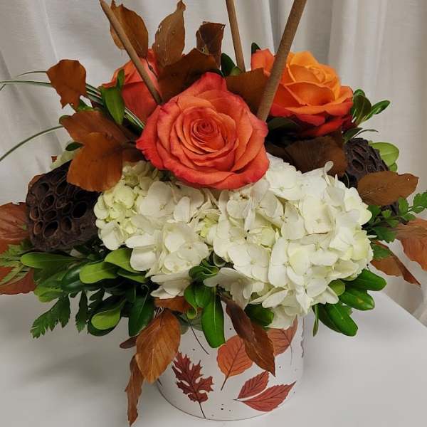 Orange roses and white hydrangeas in a leaf-patterned container