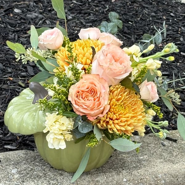 Peach roses and yellow chrysanthemums in a green pumpkin vase