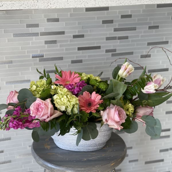 Pink roses and gerbera daisies arranged in a silver bowl vase