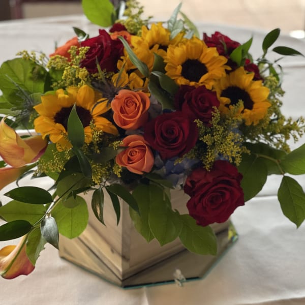 Bouquet of sunflowers and roses in a mirrored square vase