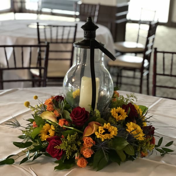 Floral centerpiece around a glass lantern with a candle