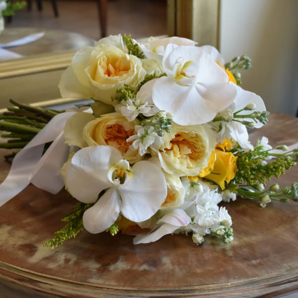 Bouquet of white orchids and pale yellow roses on a wooden table