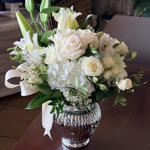 White rose and lily bouquet in a ribbed glass vase with a white ribbon