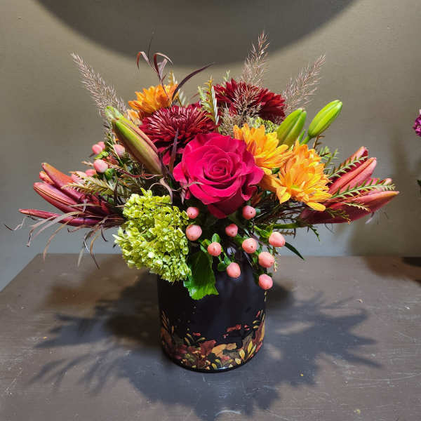 Mixed bouquet with a pink rose, lilies, and chrysanthemums in a black vase