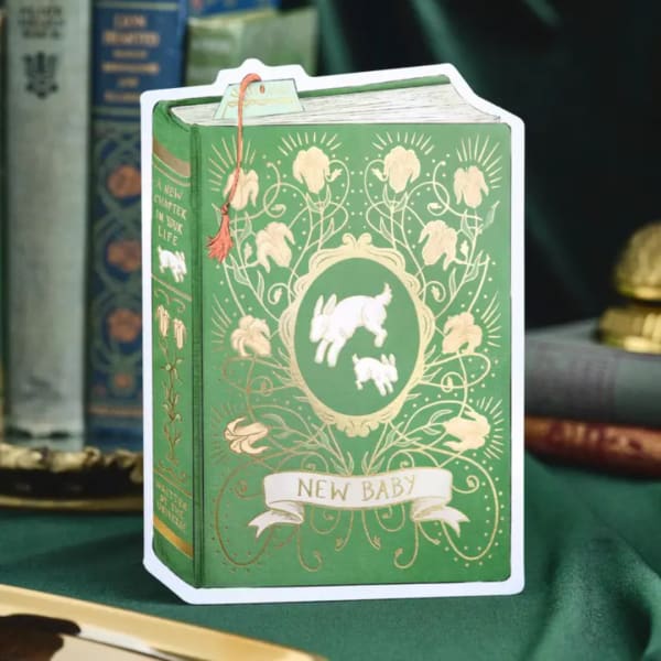 Green book-shaped gift card with rabbit illustration and "New Baby" text