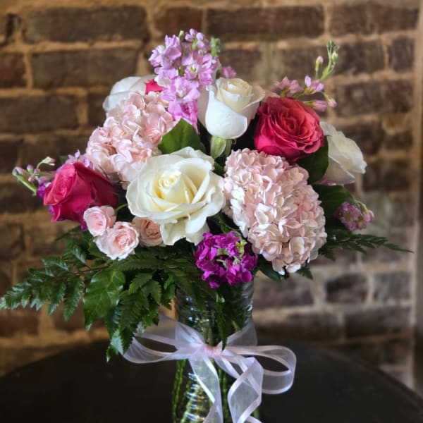 Pink and white rose bouquet with hydrangeas in a glass vase