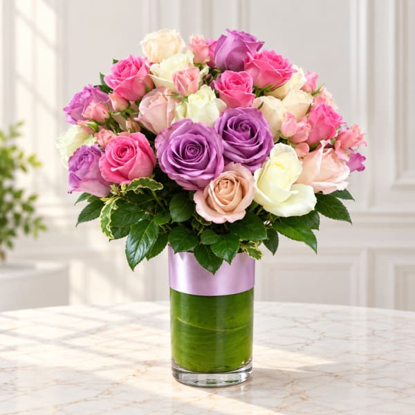 Mixed roses in pink, purple, cream, and peach in a glass vase