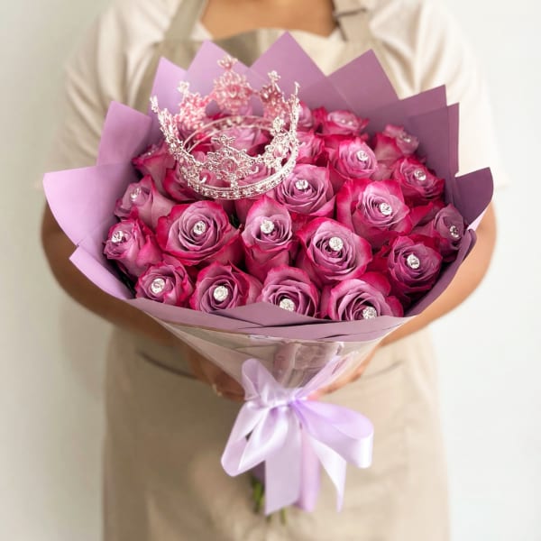 Bouquet of pink roses with a silver crown topper and lavender wrapping