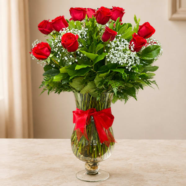 Red roses in a clear glass vase with a red ribbon