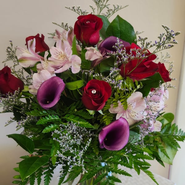 Bouquet of red roses, purple calla lilies, and pale pink flowers